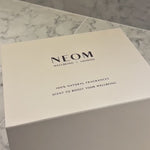 NEOM Pink Pod Mini+ and It's All Rosy 3 Wick Candle being unboxed from a gift box