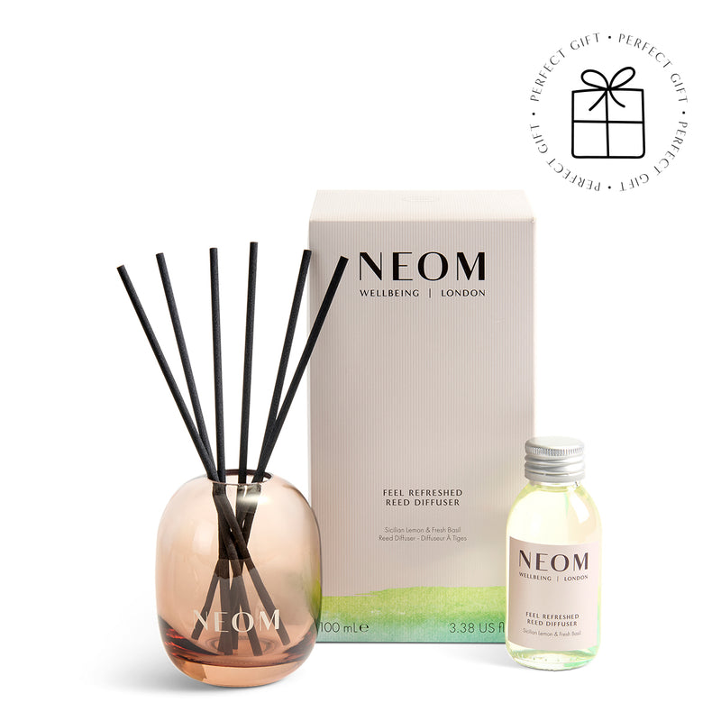 NEOM  diffuser set with rose gold diffuser, black reeds, and small bottle on a white background