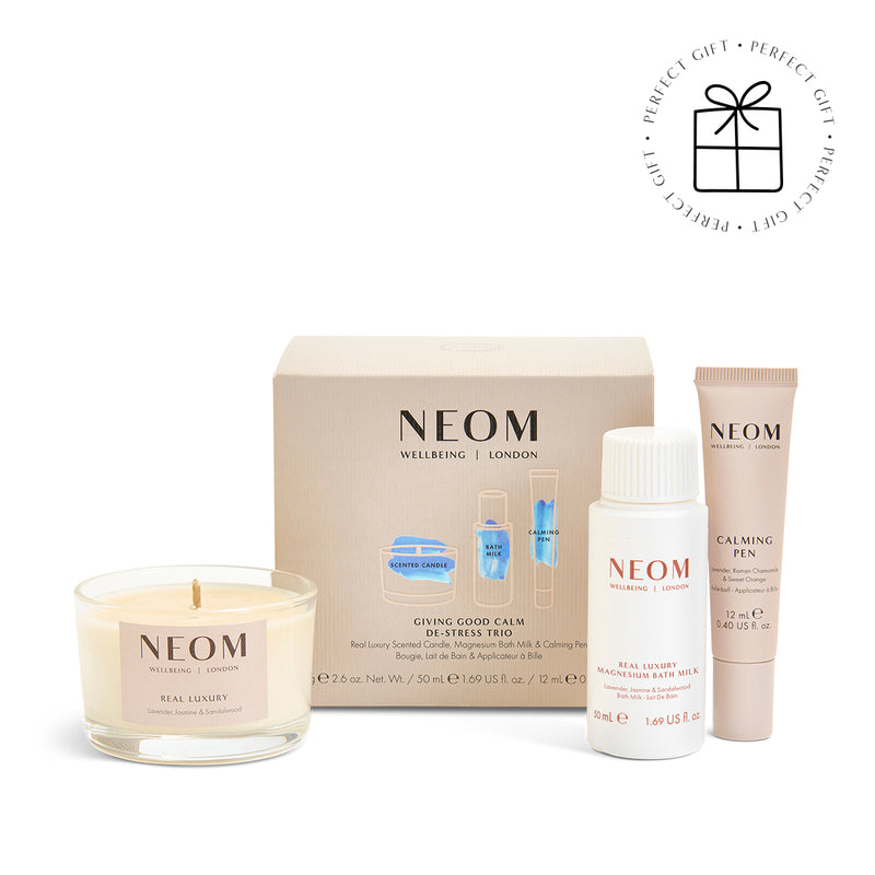 NEOM skincare and wellness products including a candle on a white background with a Perfect Gift Roundel with a present