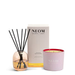NEOM happiness reed diffuser and It's All Rosy travel candle on a white background