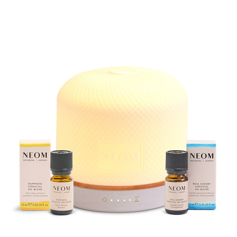 NEOM essential oil pod luxe diffuser and essential oil bottles on a white background