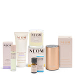 NEOM ultimate wellness bundle including sleep mist, magnesium body butter, candle, essential oil blend and pod mini plus on a white background