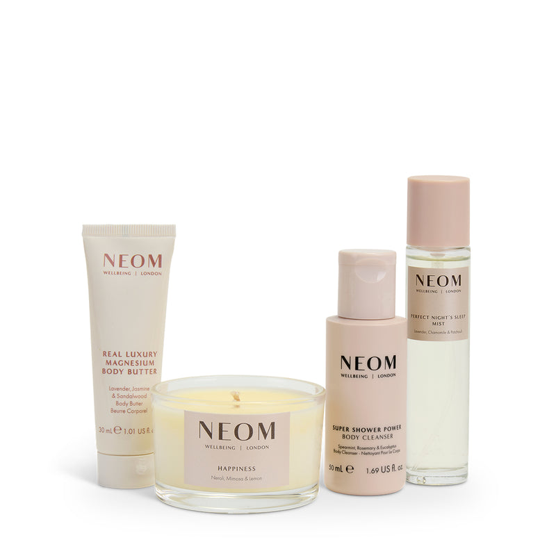 NEOM skincare products including a tube, candle, and bottles on a white background